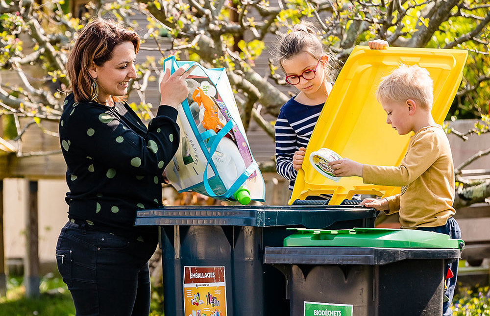 Famille qui trie des déchets dans une poubelle jaune